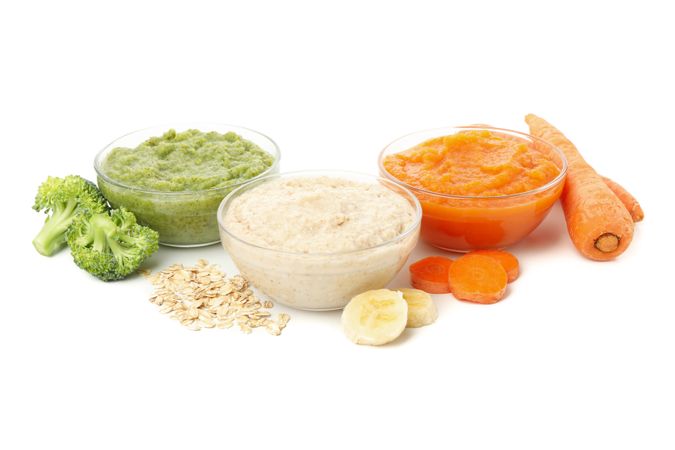 Bowls with healthy baby food isolated on plain background
