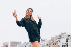 Content young woman in casual wear taking selfie at city street
