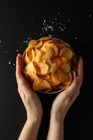 Potato chips in a bowl on a dark background