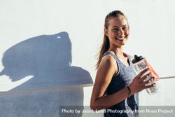 Happy female runner holding water bottle and smiling bGRWJV