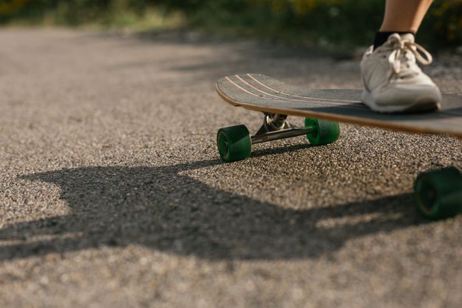 Anonymous woman riding longboard on asphalt road
