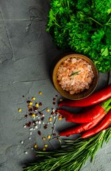 Bowl of Himalayan salt on kitchen counter with cilantro, rosemary and chili peppers