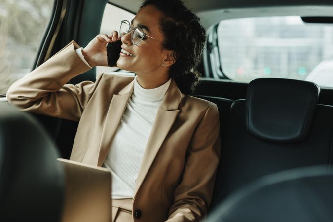 Businesswoman using phone while traveling by a car