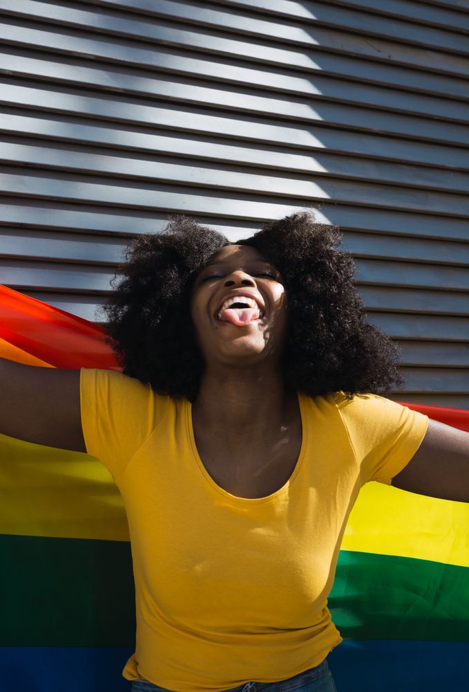 Black woman posing happily with the LGBT flag