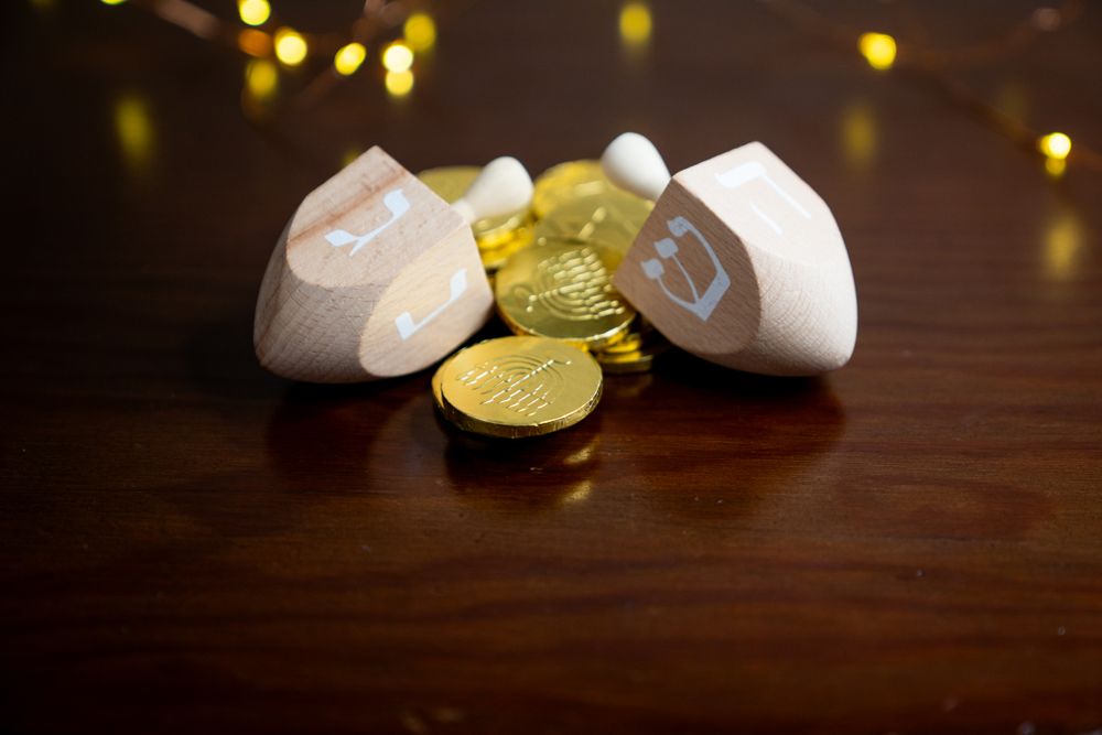 Close up of Hanukkah gelt and two wooden dreidels