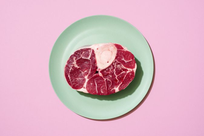 Raw beef steak above view on a pink background