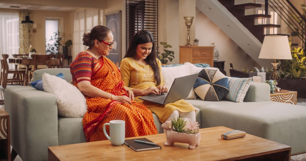 Indian Mother and Daughter Use Laptop at Home Browsing Websites