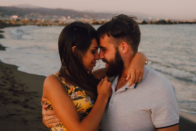 Amorous man carrying woman on arms along sandy beach