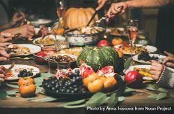 Group of people at festive fall dinner with wine, squash, olives, decorative roast pan 56NZx5