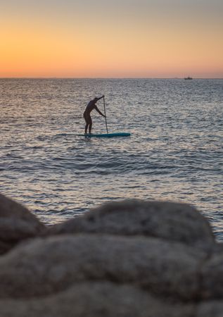 Man practicing paddle surfing with neoprene in a sunrise