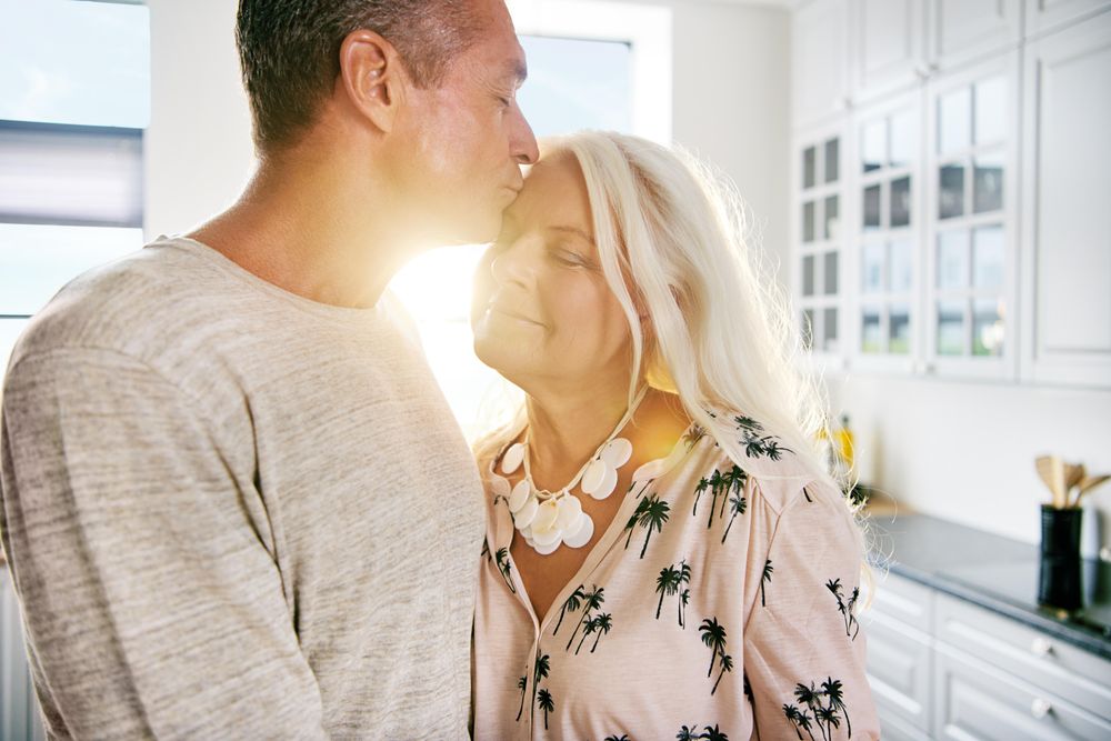 Older man kissing his beautiful grey haired partner on the forehead