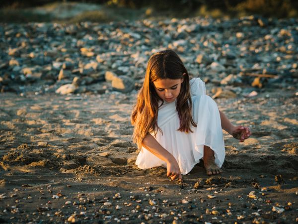Adorable girl playing with sand on beach