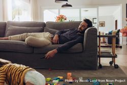 Man relaxing on couch with his kid playing on floor bG3Nlb