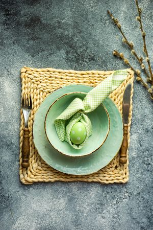 Top view of Easter holiday table setting with pastel egg wrapped in bunny napkin