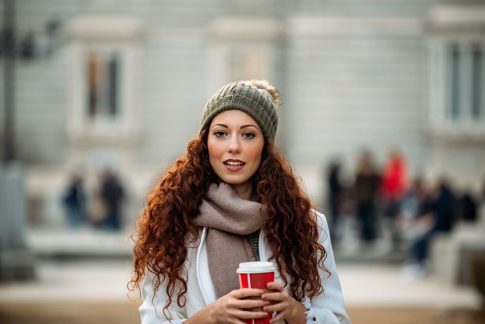 Woman drinking coffee wandering in the streets of Madrid on winter