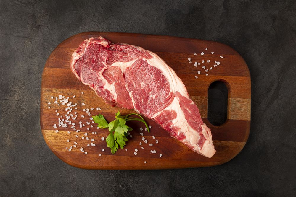 Raw ancho meat ready to roast on a wooden cutting board.
