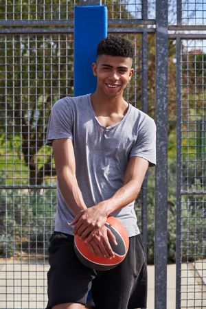 Smiling Hispanic sportsman with ball on street