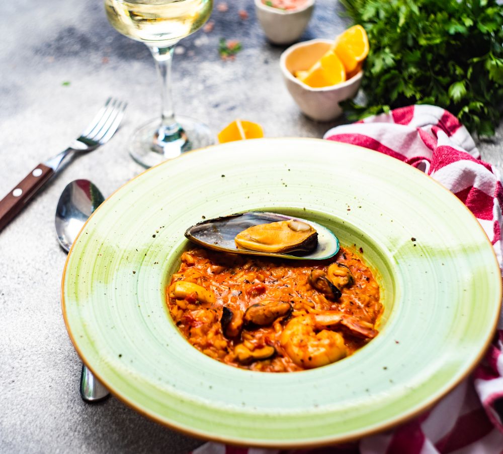Risotto with sea food in green bowl with lemon slices