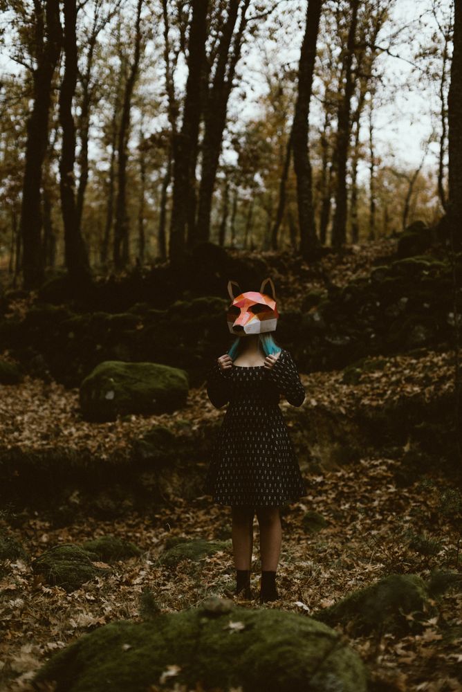 Woman in red fox mask walking in forest