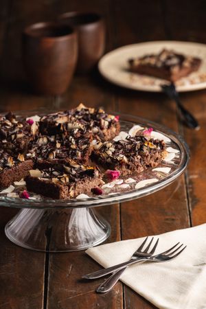 Tasty brown cake decorated with flakes on glass plate