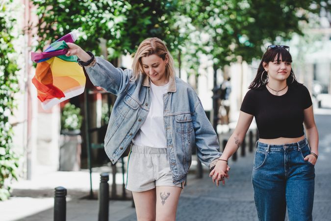 Lesbian couple with LGBT flag walking on street