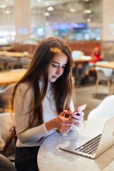 Serious brunette woman in a restaurant texting on her smart phone
