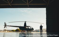 Man walking into a hangar with helicopter parked outside 5o9Vkb