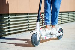 Close up of female legs going around the city with an electric scooter