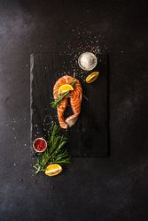 Salmon fish with rosemary and lemon on dark counter with copy space