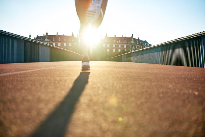 Female joggers legs going across a bridge in the morning sun