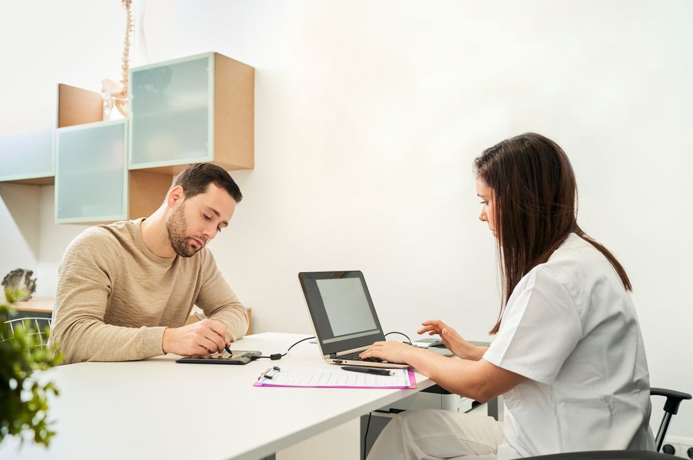 The physical therapist and the patient fill out a patient form.