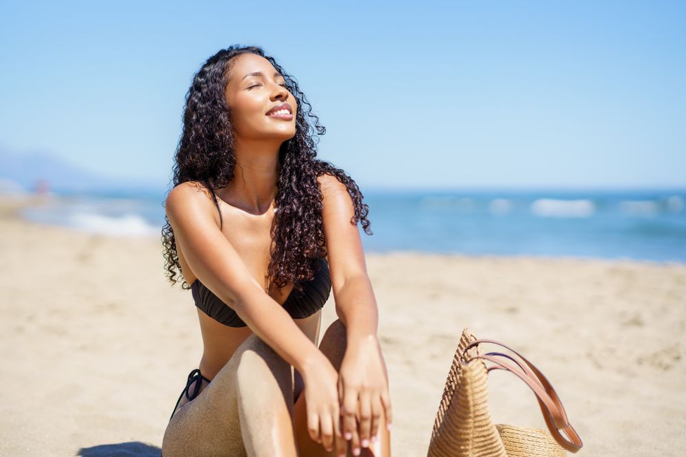 A Joyful Young Woman Enjoying and Relaxing on the Beautiful Beach by the Sunny Ocean