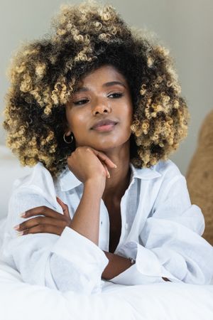 Thoughtful Black woman lying on bed in bedroom