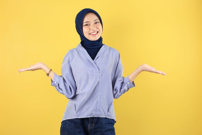 Cheerful Young Asian woman in Blue Shirt and Navy Hijab Celebrating Success