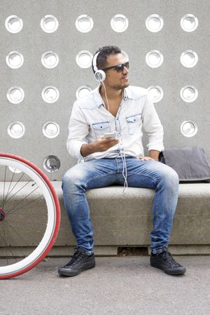 Male looking into distance while listening to something amusing on phone while sitting with bike