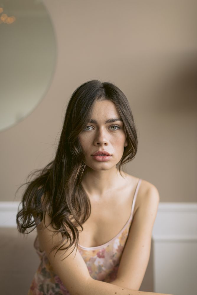 Young woman starring into the camera while sitting with her arms rested in front of her