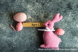 Easter card concept of grey counter with decorative small pink eggs and rabbit ornament bDjaGK
