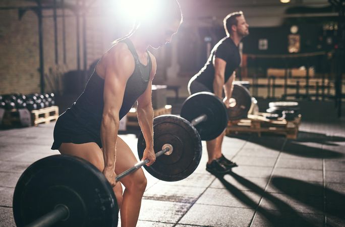 Strong couple using proper deadlift form to lift heavy barbell