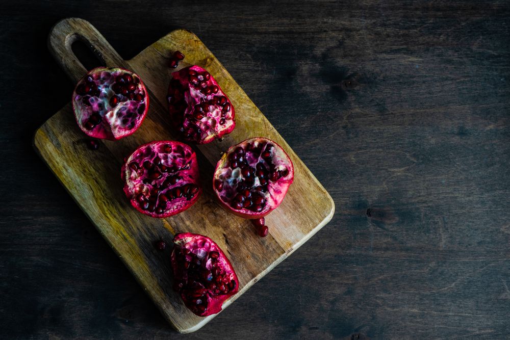 Top view of open pomegranates on wooden cutting board