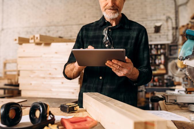 Bearded man using his tablet In carpentry studio