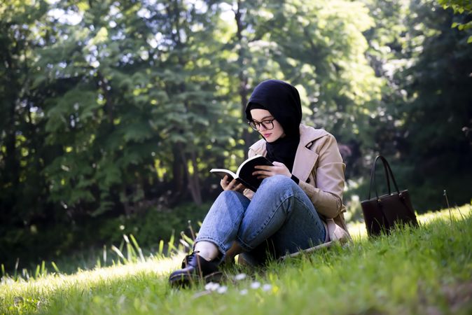 Middle Eastern woman engrossed in a book in the park