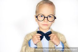 Serious blond boy in glasses fixing his bow tie 5lkm60