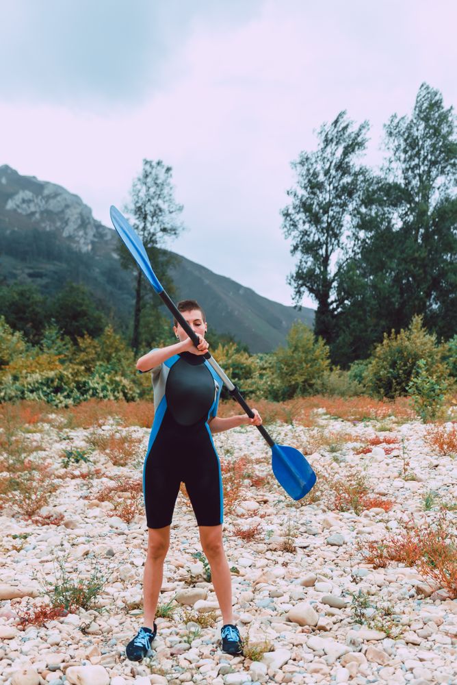 Female standing with paddle on shore