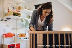 Woman putting her baby to sleep in crib 5qxKq0