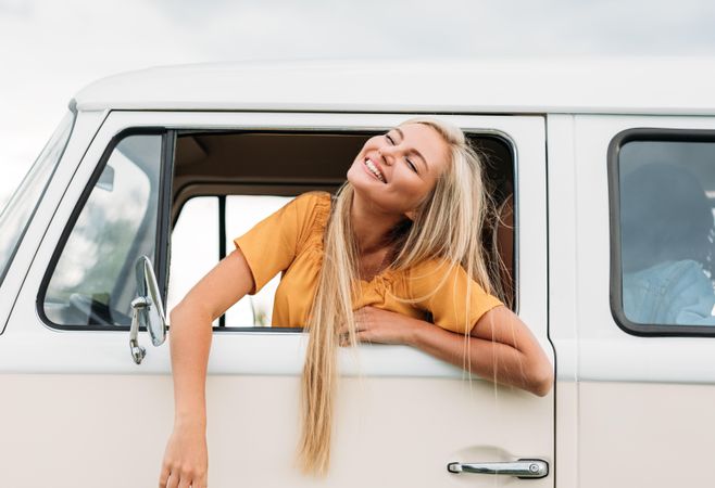 Woman leaning out of car window looking up and smiling