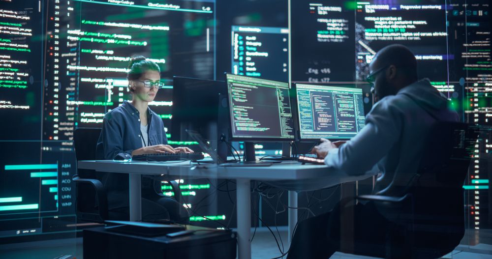 Portrait of Two Diverse Developers Working on Computer, Typing Lines of Code that Appear on Big Screens Surrounding Them.