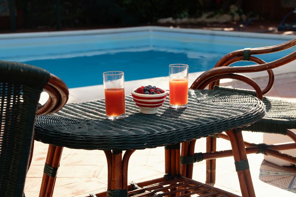Healthy breakfast with fresh berries and juice served on a table by the pool at a luxury resort