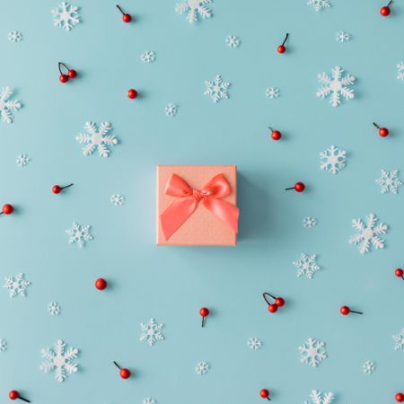 Christmas pattern made of snowflakes and red berries with orange present on blue background