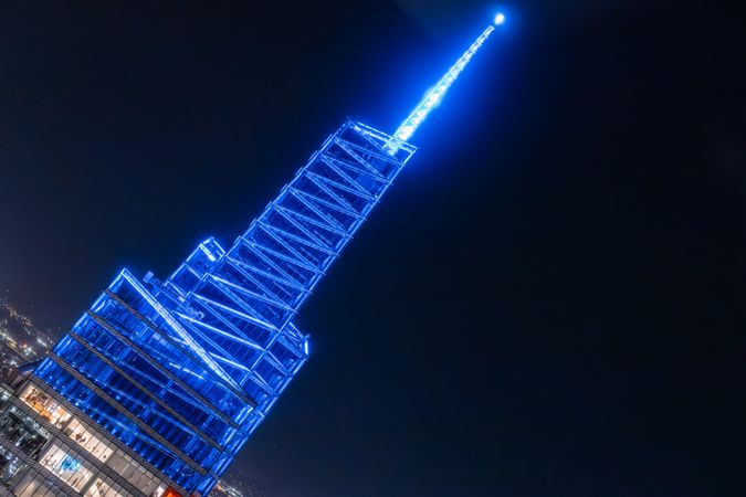 Aerial View of Lower Manhattan Architecture. Night Image of Financial Business District from a Helicopter. Modern Glass Office Tower with Blue Light Spire Illumination
