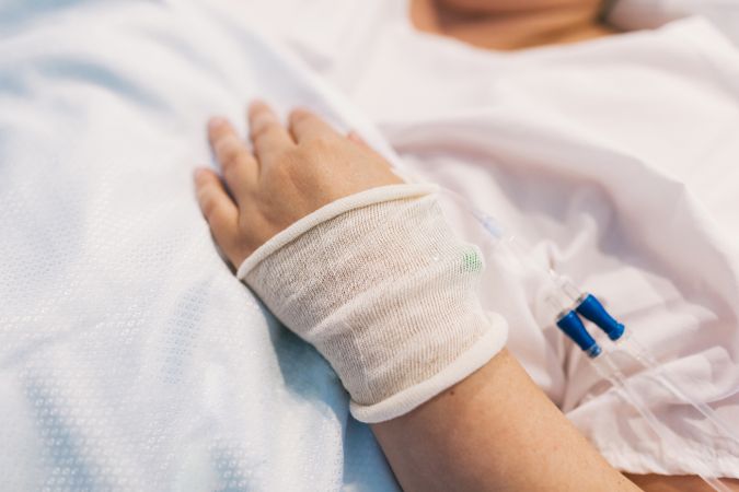 Crop woman with intravenous cannula on hospital